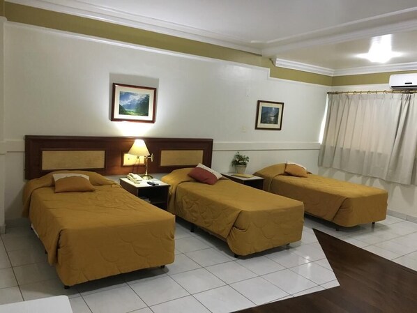 A hotel room with two single beds, a nightstand with a lamp, a small table, and a window with curtains. - Tamareiras Park Hotel (Uberaba)