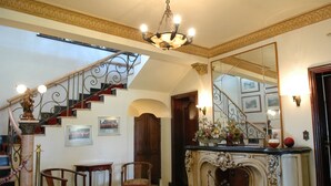 A grand room with a staircase, a fireplace, and a large mirror. - Tamareiras Park Hotel (Uberaba)