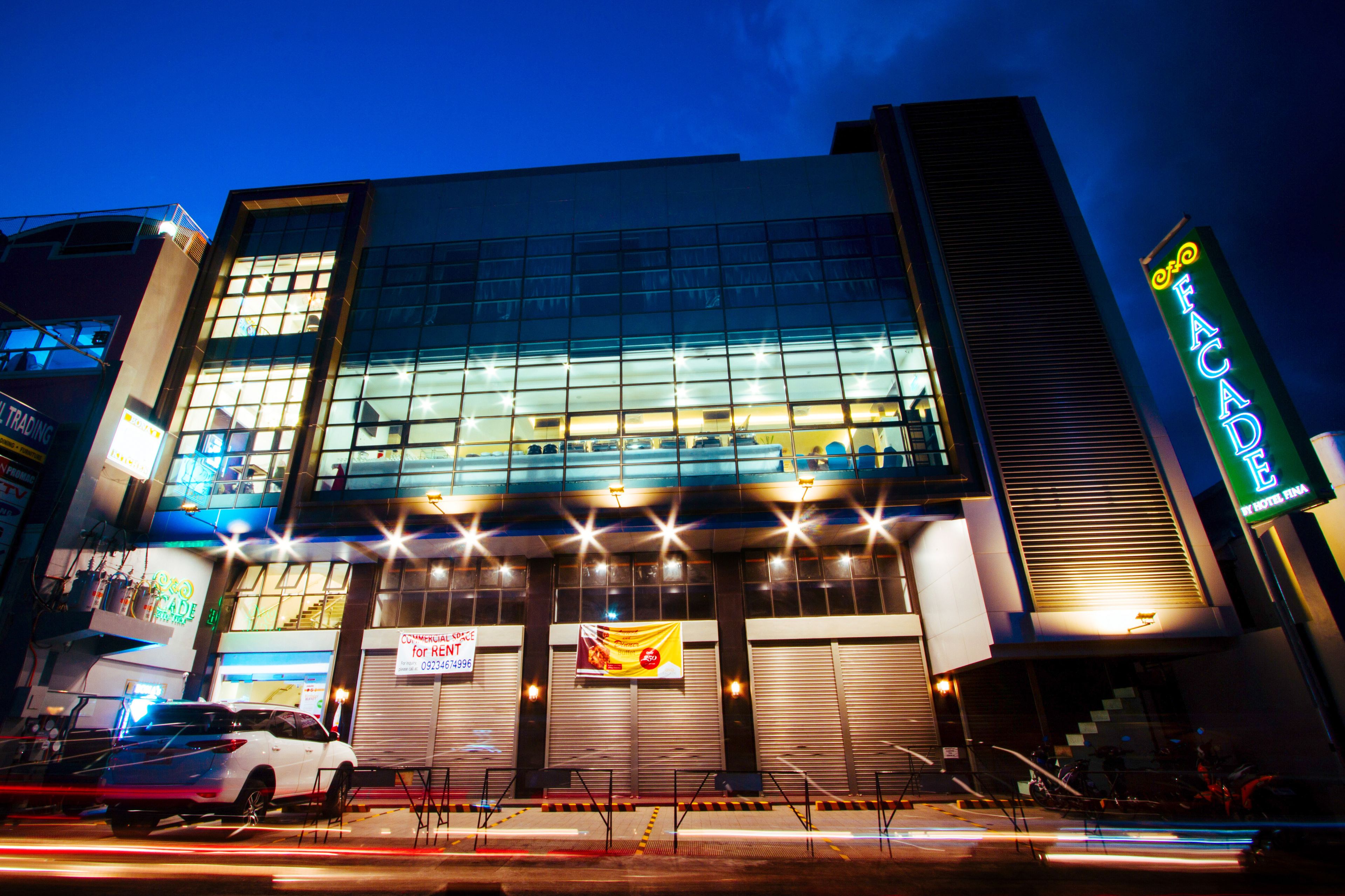 A modern hotel with a glass facade, multiple floors, and a prominent entrance with a staircase.
