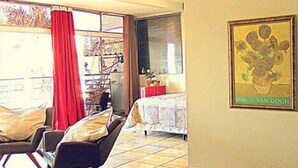 A spacious living area with a dining table, chairs, a red rug, and a chandelier. - Pousada Beira Rio (Itumbiara)