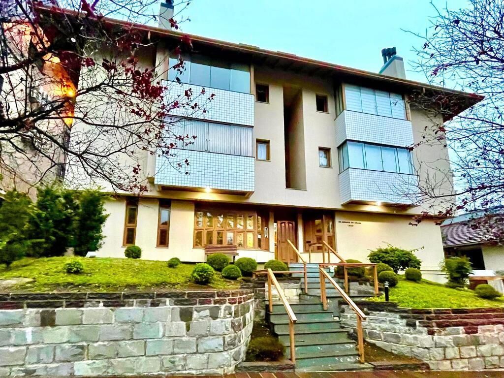 Un edificio de dos plantas con fachada de piedra, una entrada central y una escalera que lleva a ella.