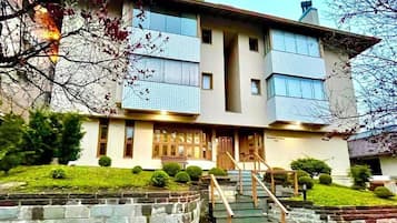 Un edificio de dos plantas con fachada de piedra, una entrada central y una escalera que lleva a ella.