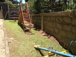 Un parque infantil con un sube y baja y una escalera roja.