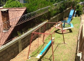 Ein umzäunter Garten mit Schaukel und Rutsche.