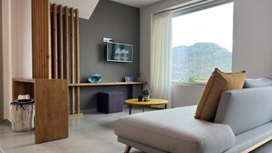Una sala de estar moderna con un sofá, una mesita redonda, un separador de madera y un ventanal con vistas a la montaña.