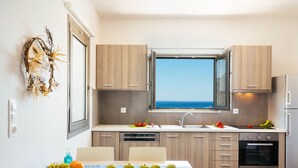 Una cocina moderna con armarios de madera, horno empotrado y ventana con vistas al mar.