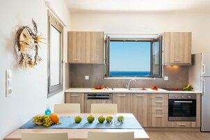 Une cuisine moderne avec des meubles en bois, un four encastré et une fenêtre donnant sur la mer.
