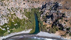 Vista aérea de una zona costera con un canal estrecho, terreno rocoso y vegetación escasa.