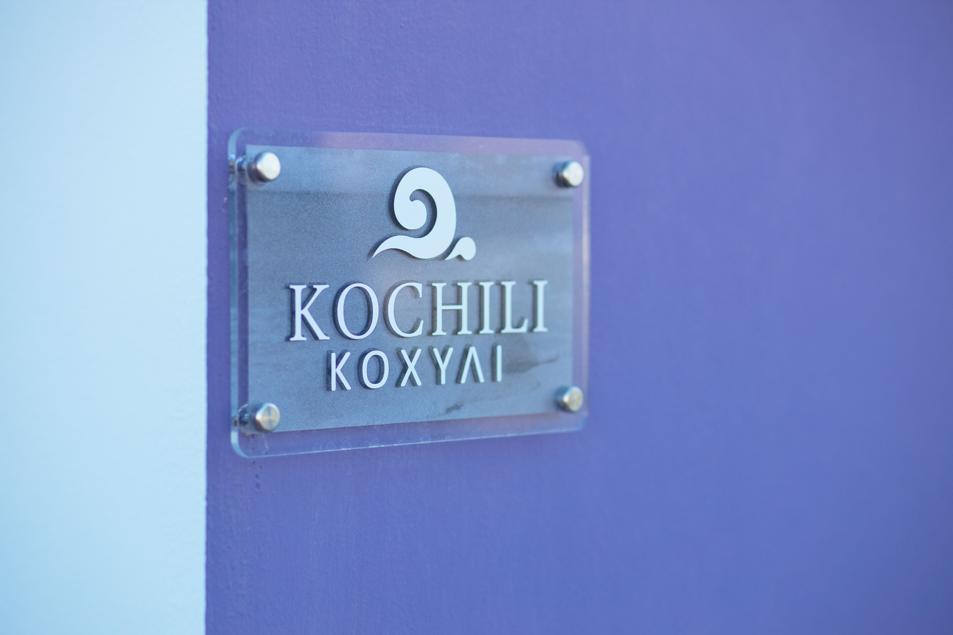A sign with the name "KOCHILI KOXYAI" on a purple wall.