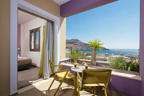 A balcony with a table, chairs, and a view of the sea and mountains. - Sea View Luxury Apartments (Agios Vasileios)