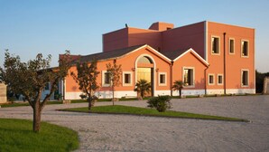 A modern building with a flat roof, a central entrance with an arch, and a symmetrical facade. - Agriturismo Arangea (Lequile)