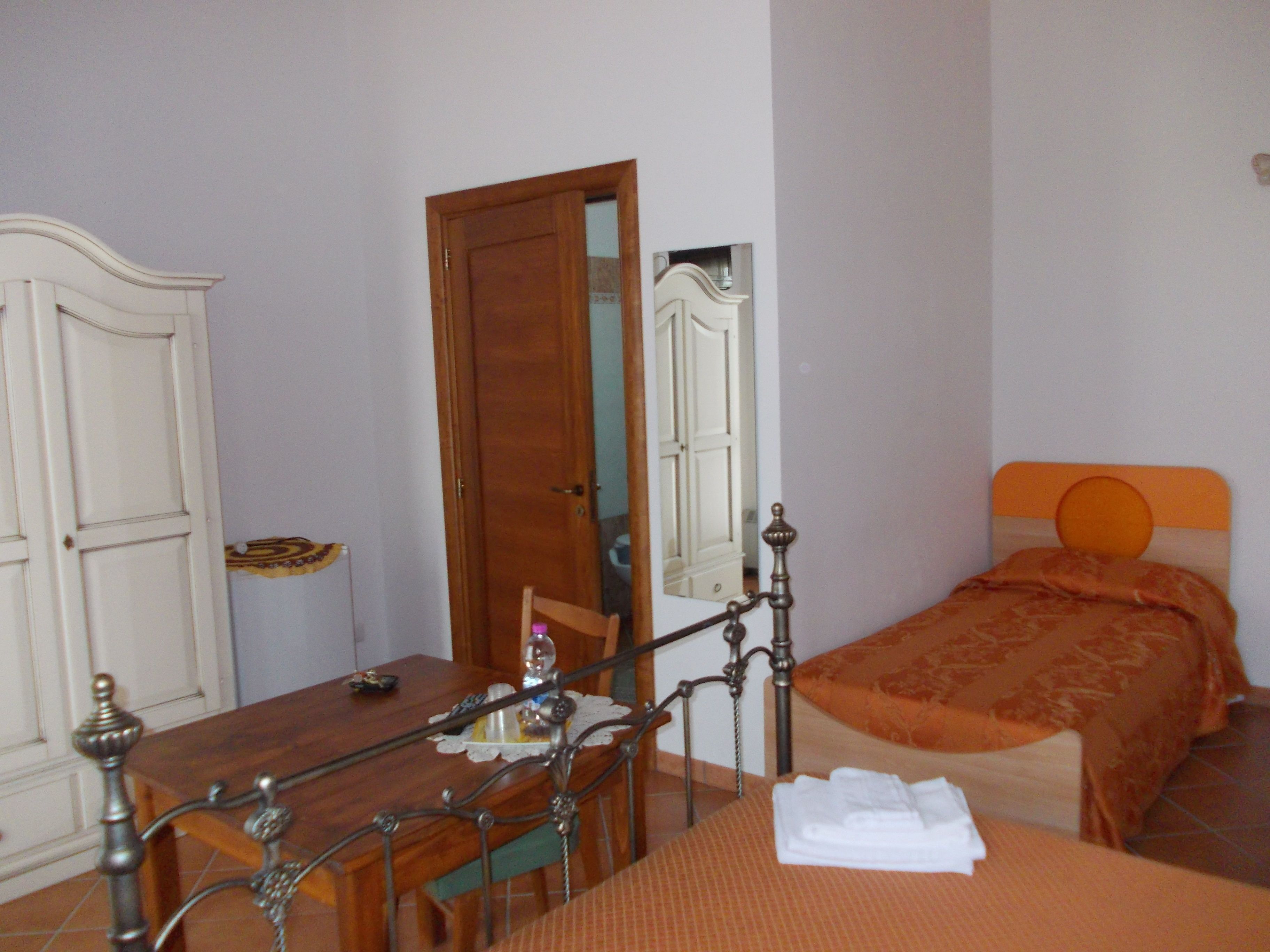 Un dormitorio con cama de madera, una mesita de noche, un espejo y un armario.