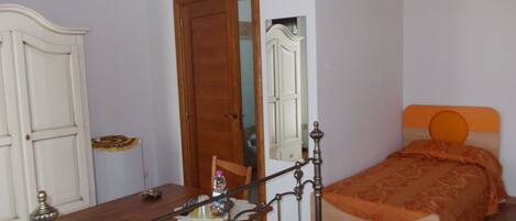 Un dormitorio con cama de madera, una mesita de noche, un espejo y un armario.
