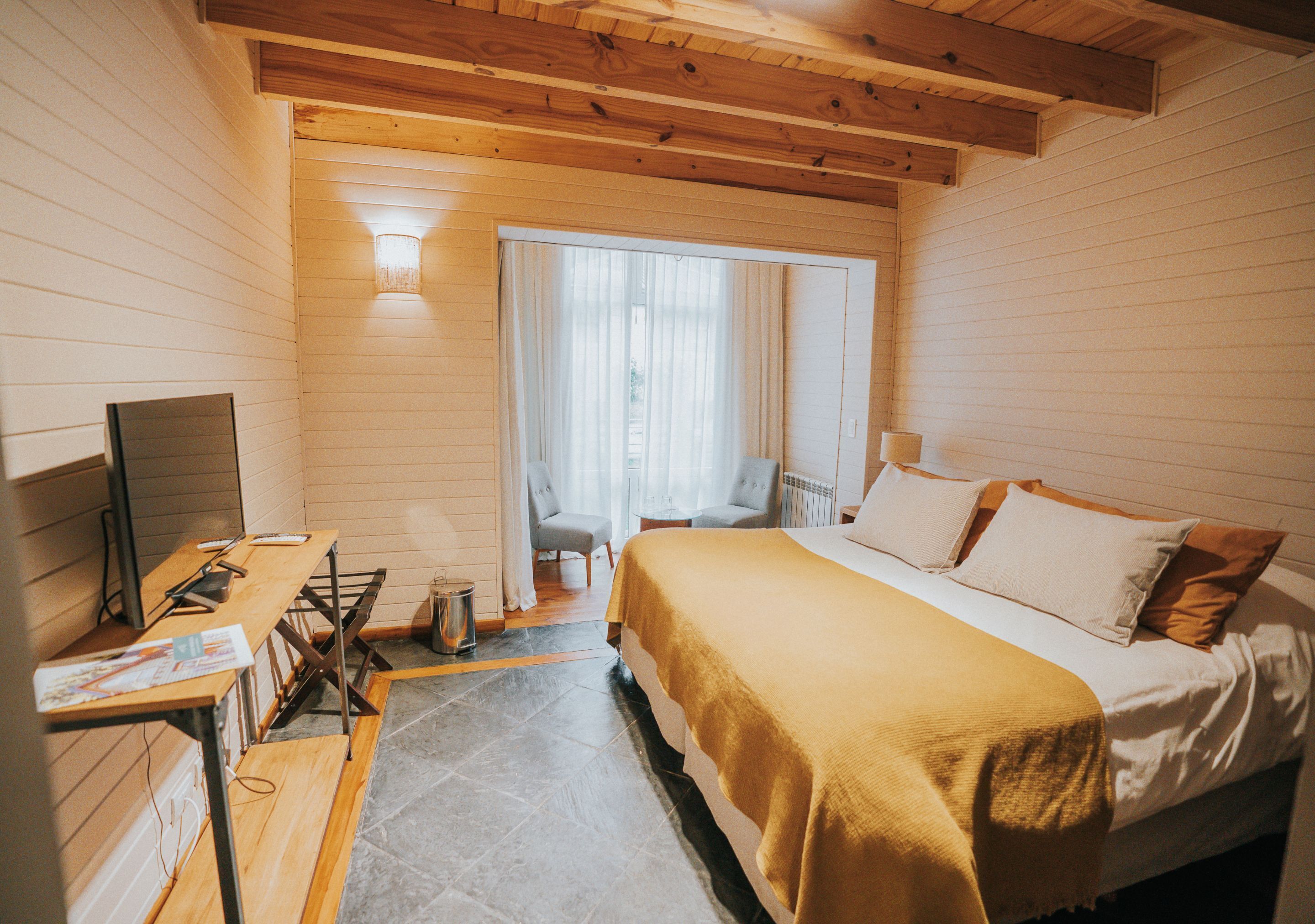 Una habitación con una cama, un escritorio, una silla y una mesita.