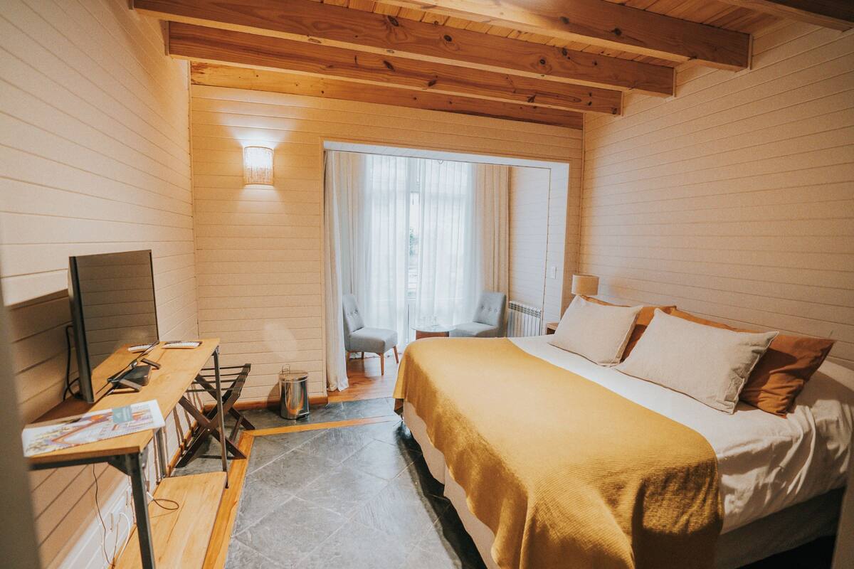 A room with a bed, a desk, a chair, and a small table.