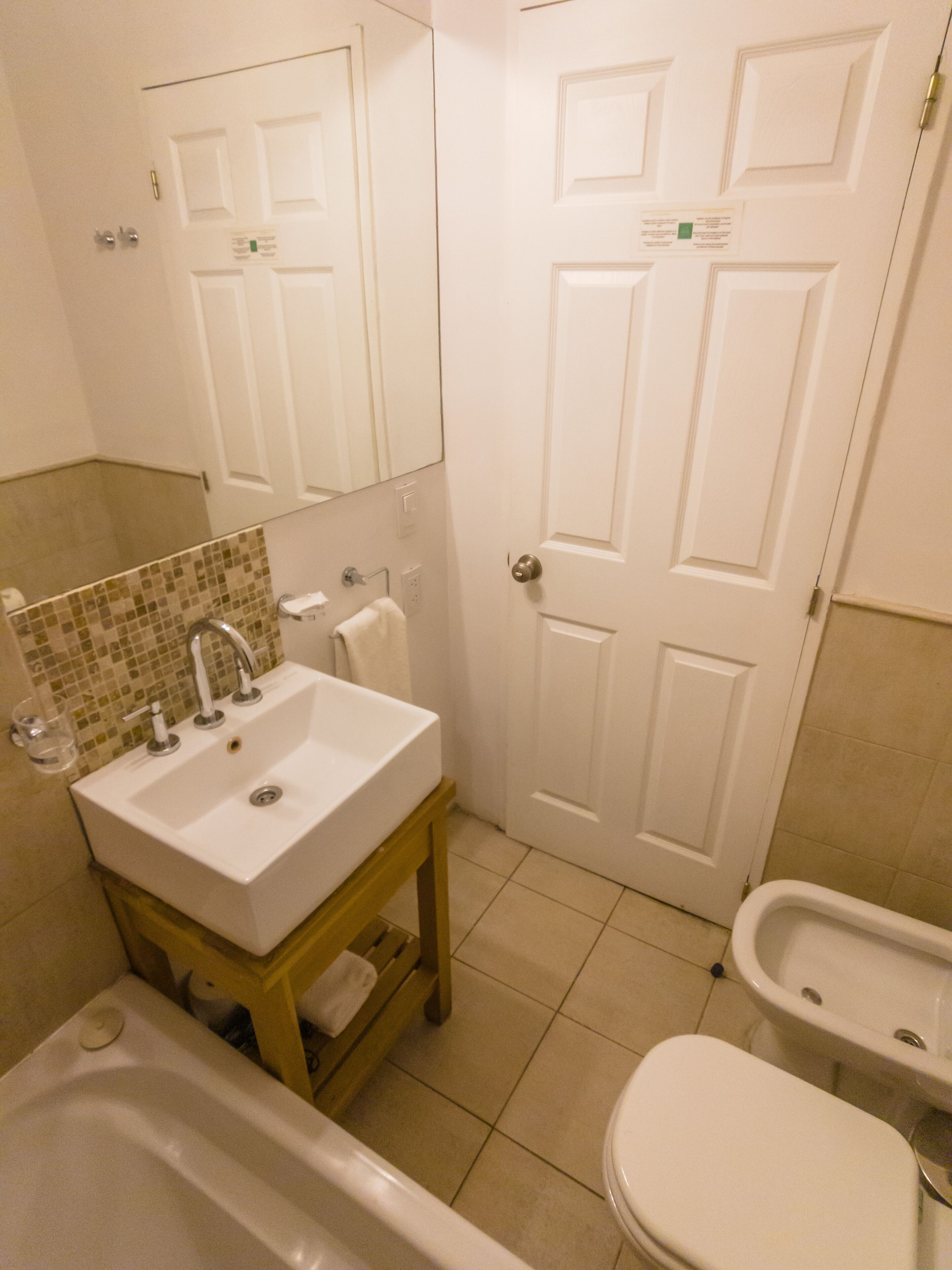 Un baño con lavamanos, espejo, inodoro y bañera.