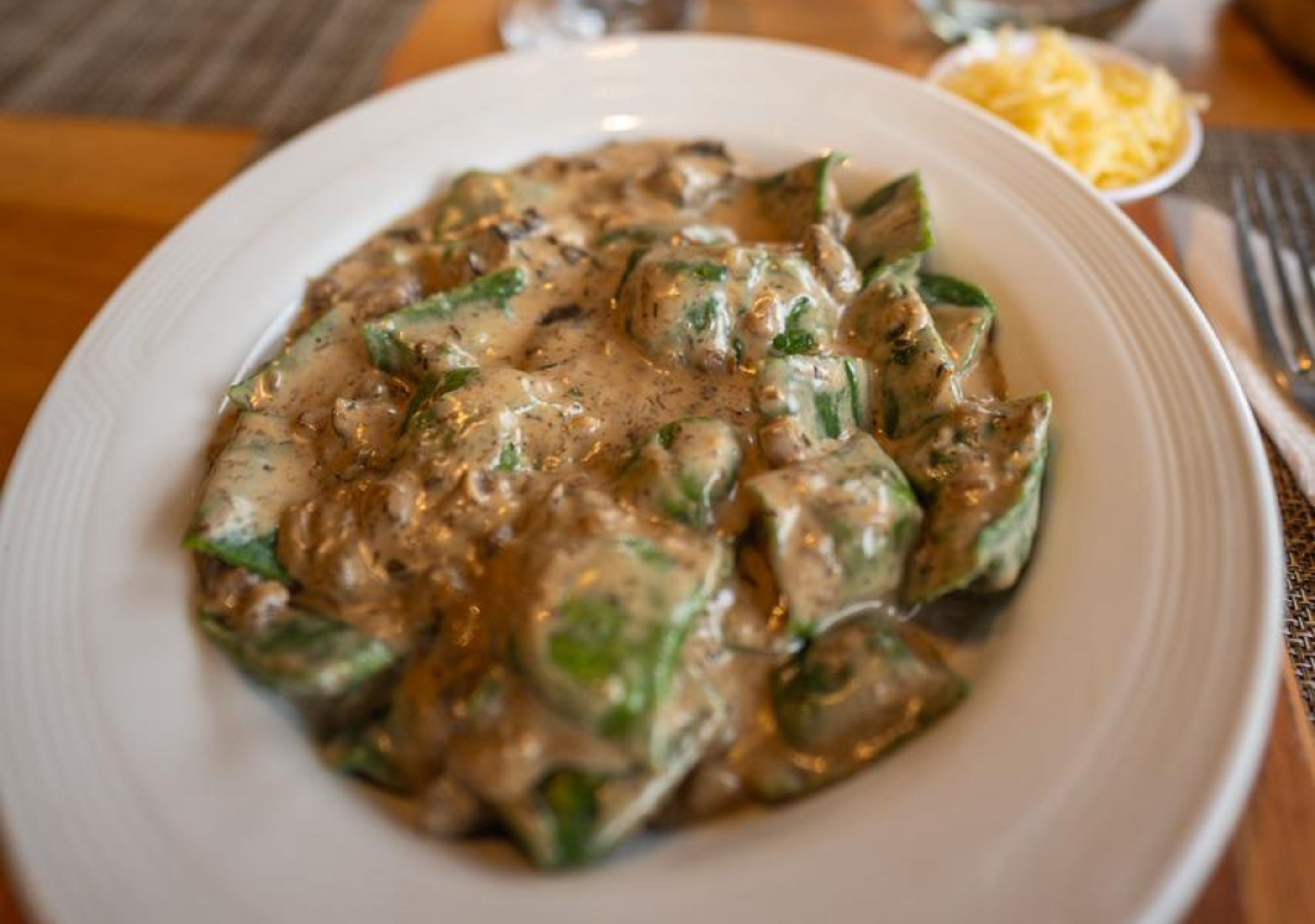 A plate of food with a creamy sauce and green vegetables.