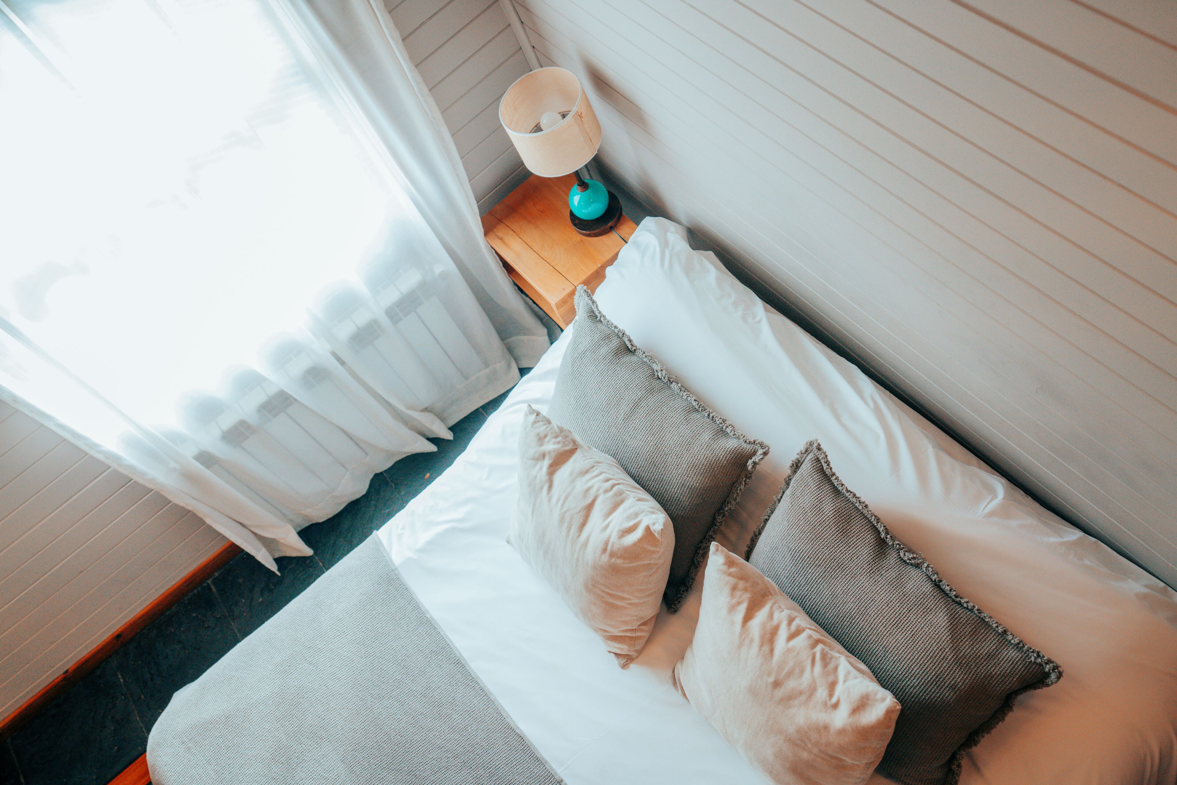 A neatly made bed with pillows and a bedside table with a lamp.