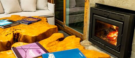 Una habitación acogedora con chimenea, un sofá y una mesa de centro con libros.