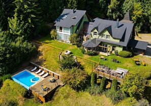 Une grande maison avec une piscine, une terrasse et du mobilier d’extérieur.