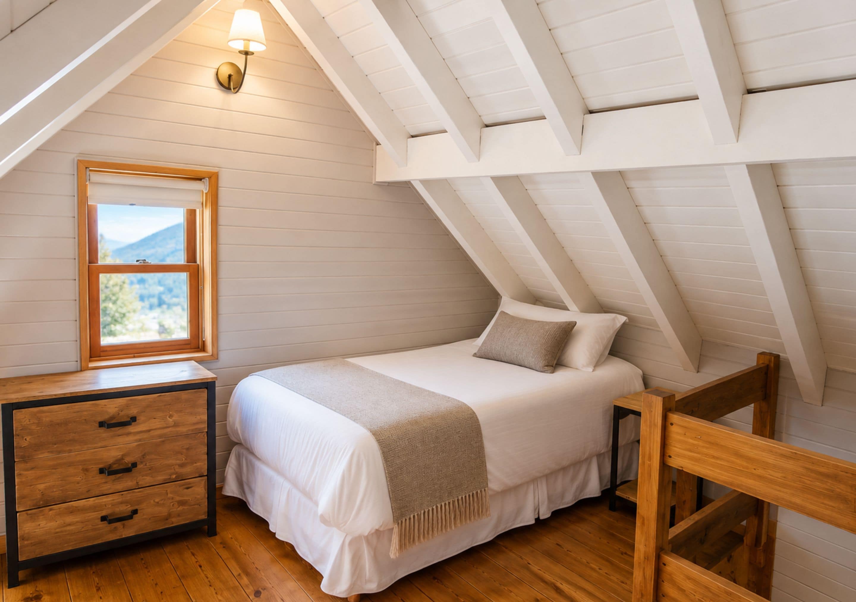 A bedroom with a bed, a nightstand, a window with a view, and a sloped ceiling.