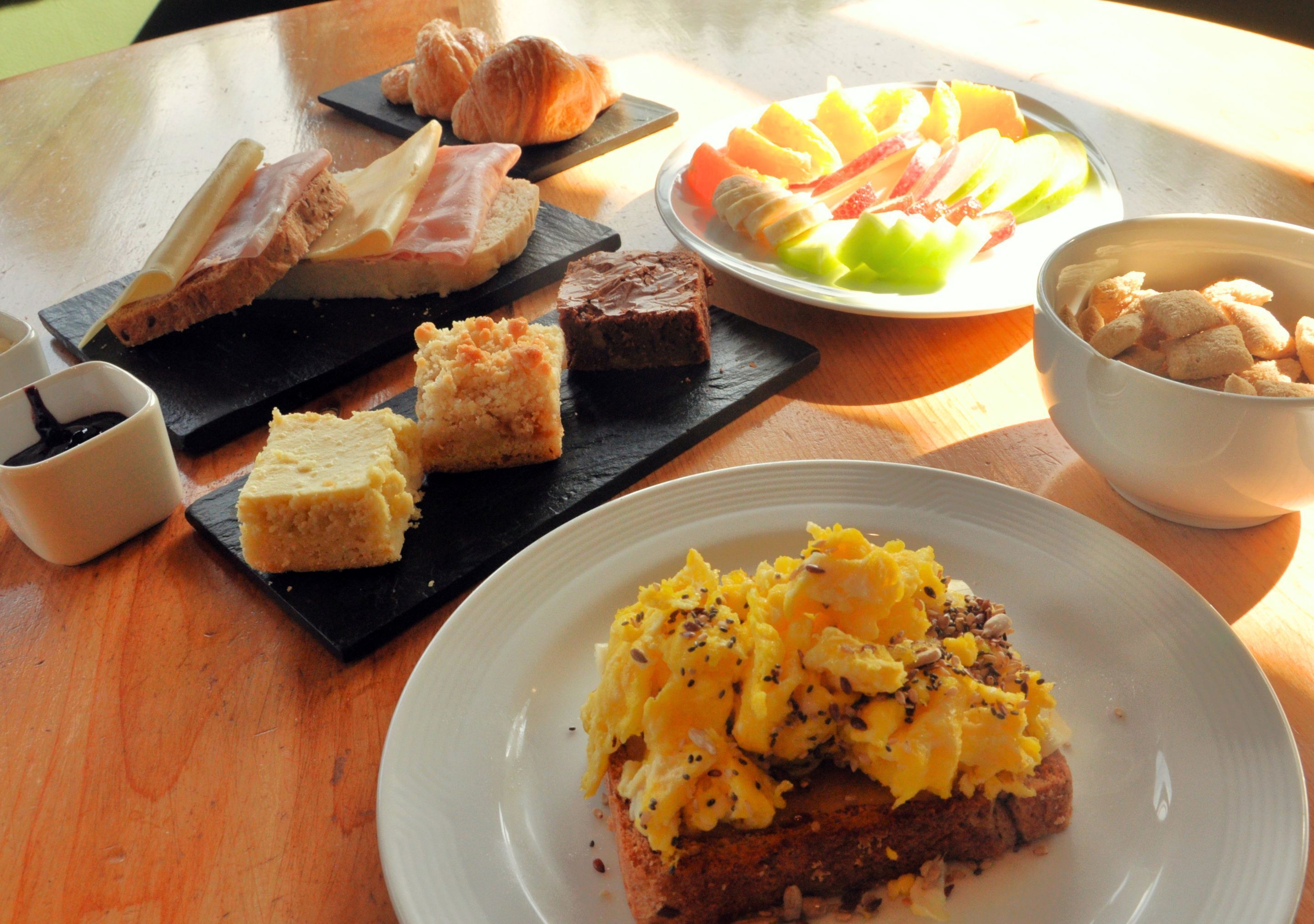 Une table de petit-déjeuner avec divers aliments, notamment du pain, des viennoiseries et des fruits.