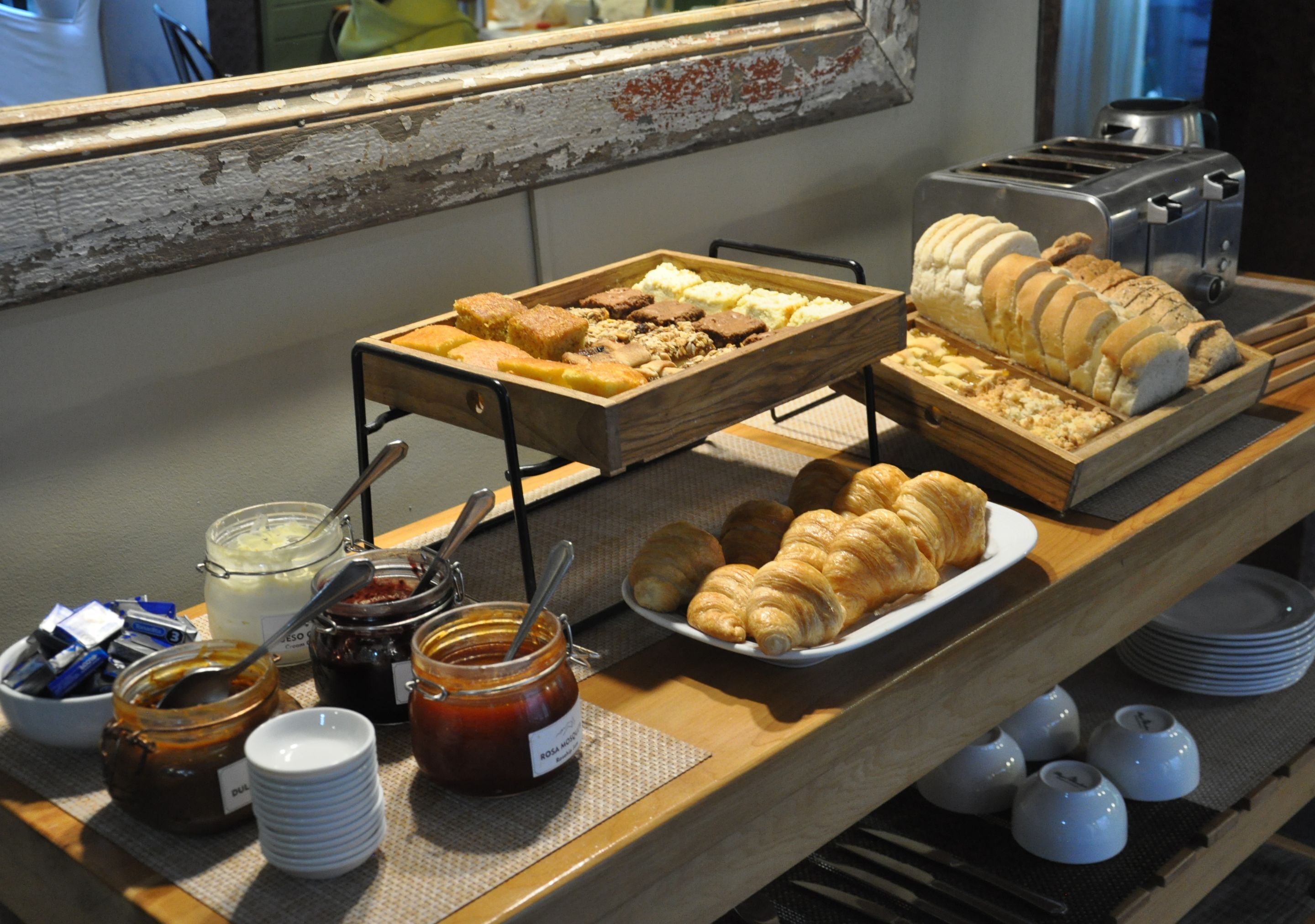 A buffet with various food items, including pastries and bread, arranged on wooden stands.