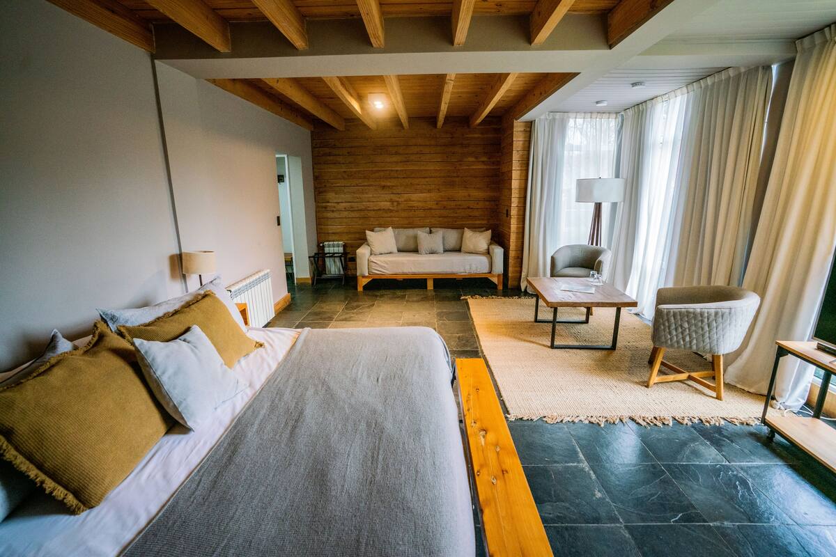 A cozy room with a bed, a sofa, a chair, and a table.