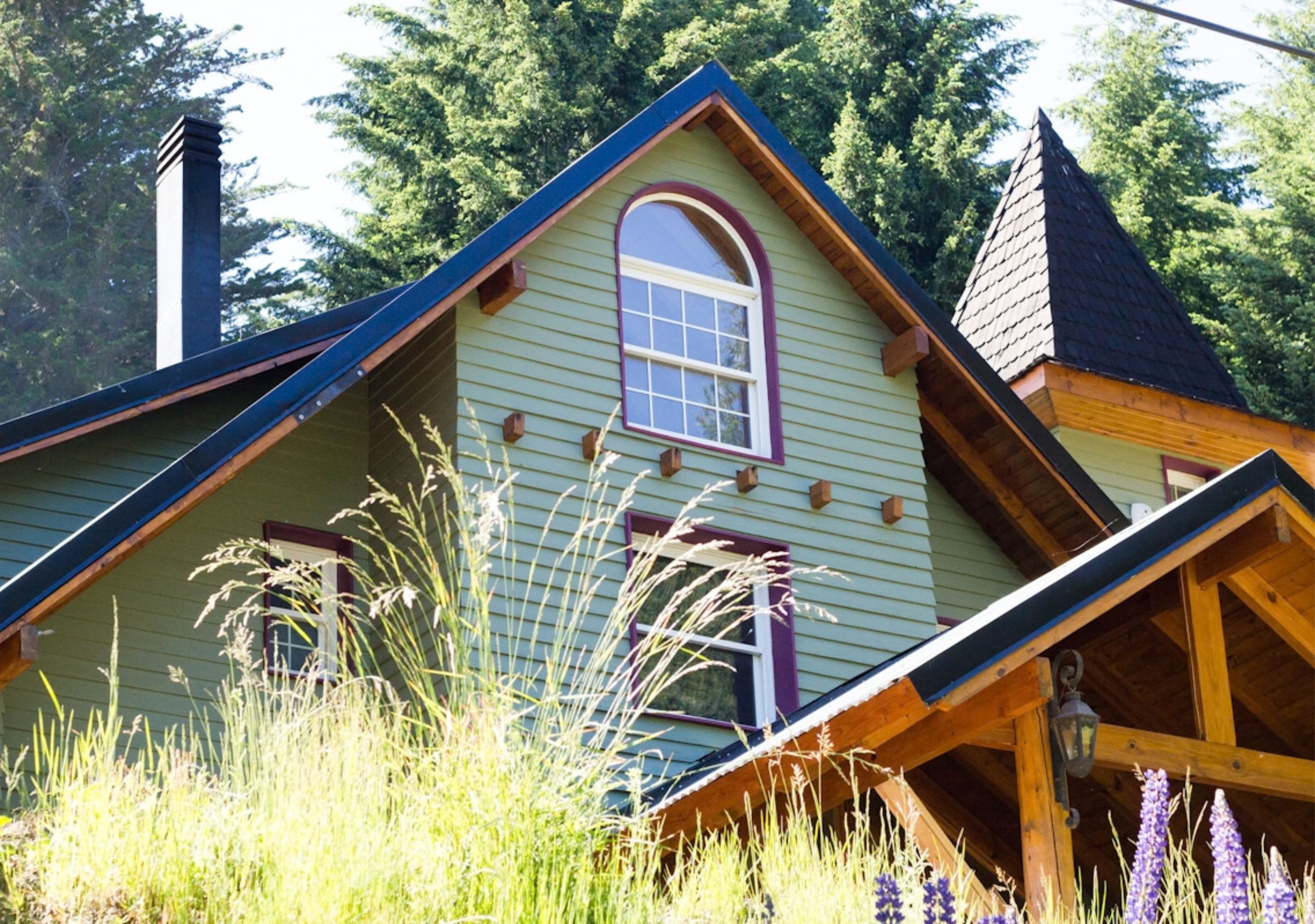 A house with a steeply pitched roof, a prominent chimney, and a window with a purple frame.