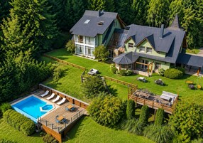 Una casa grande con piscina, terraza y mobiliario exterior.
