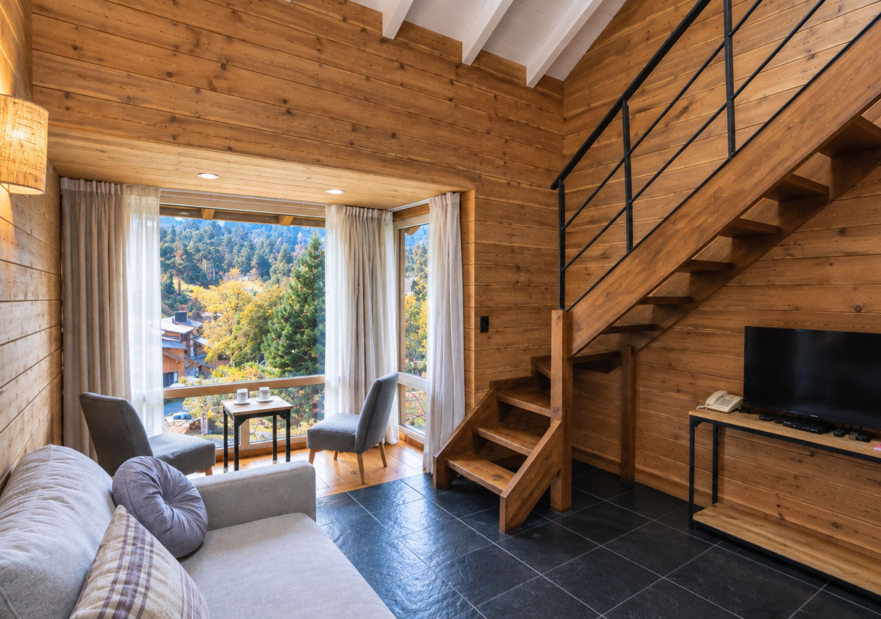 A wooden interior with a sofa, chairs, a TV, and a staircase.