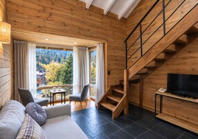 Un interior de madera con un sofá, sillas, un televisor y una escalera.