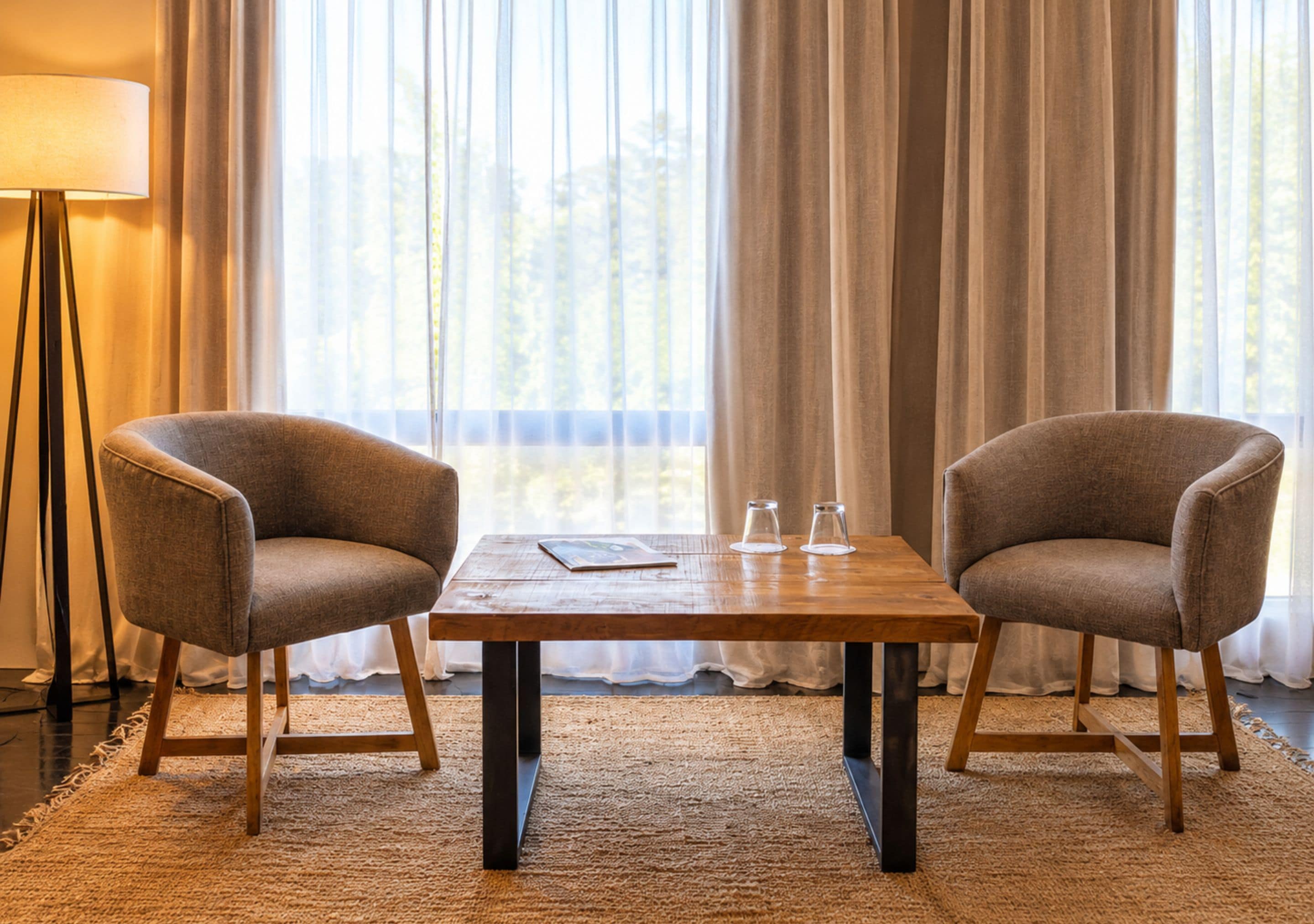 A room with two armchairs, a wooden table, and a floor lamp.