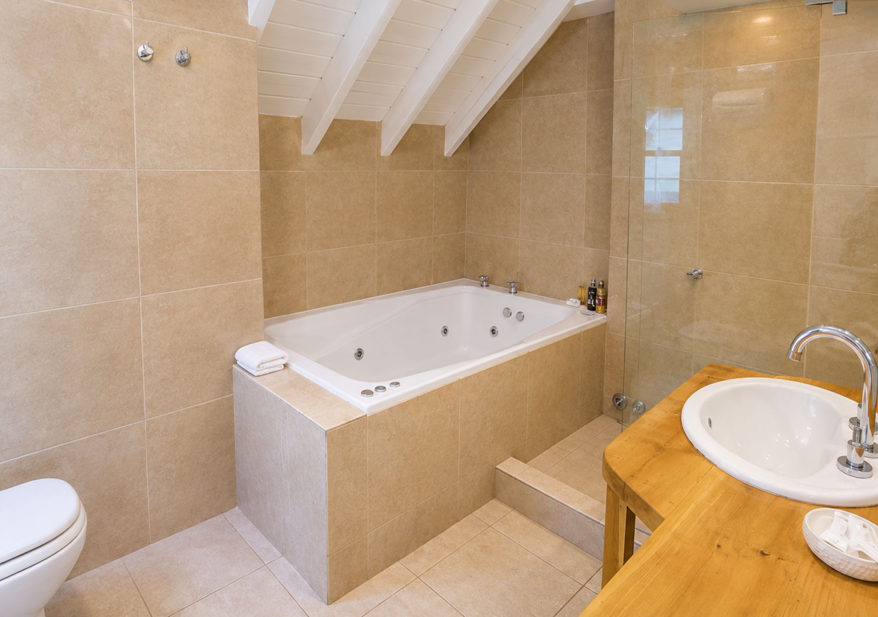 Een moderne badkamer met een vrijstaand bad, een houten wastafelmeubel en een wit toilet.