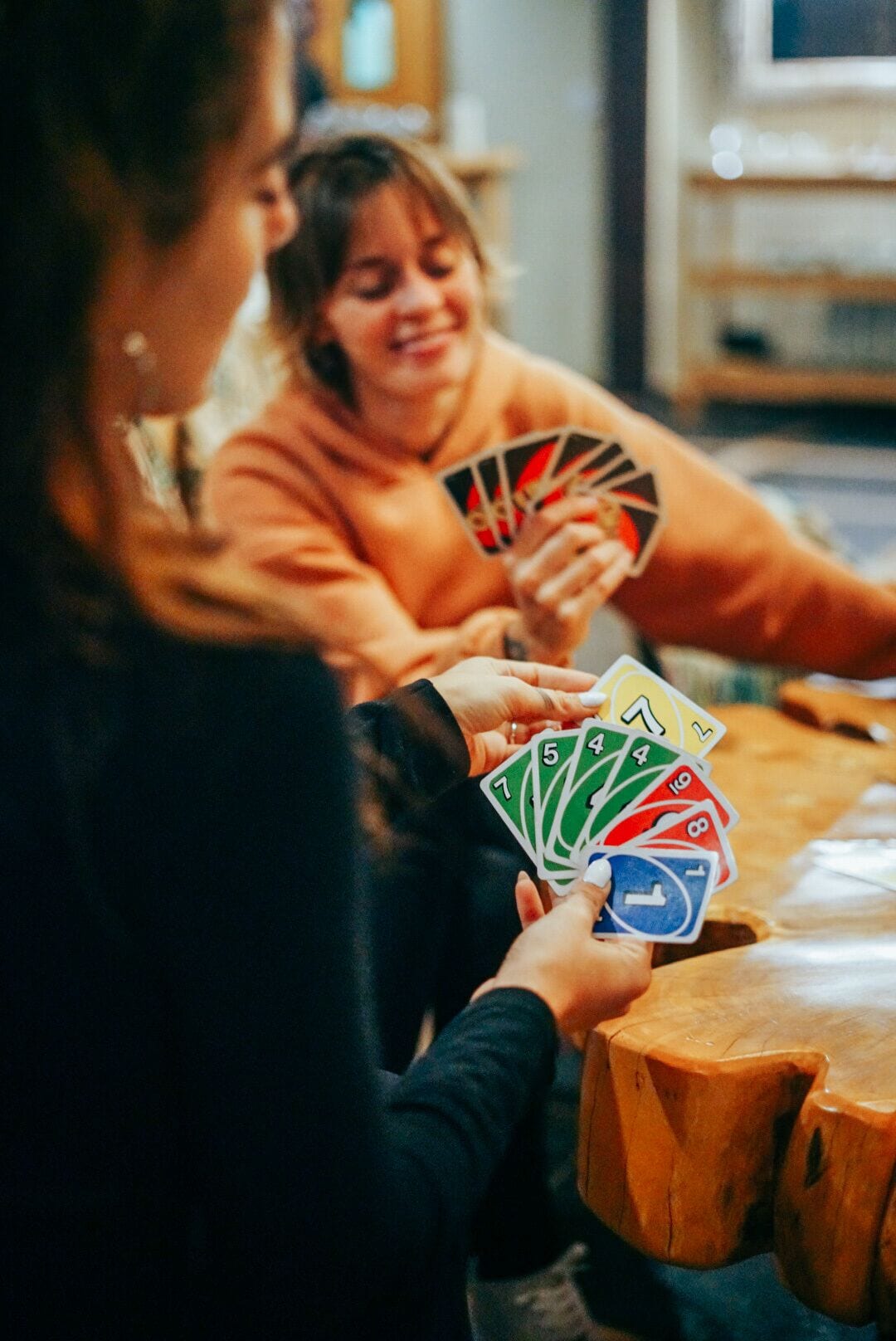 Two people playing cards at a wooden table.