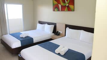 Una habitación de hotel con dos camas, cada una con cubrecama azul y ropa de cama blanca, y un cuadro abstracto colorido en la pared.