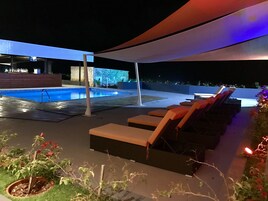 Una piscina al aire libre, sillones reclinables de piscina