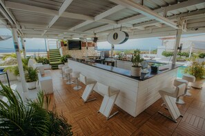 En bar med udsigt til stranden, hvide barstole og plantekasser.