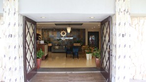 La entrada de un hotel con mostrador de recepción, zona de estar y plantas en macetas.