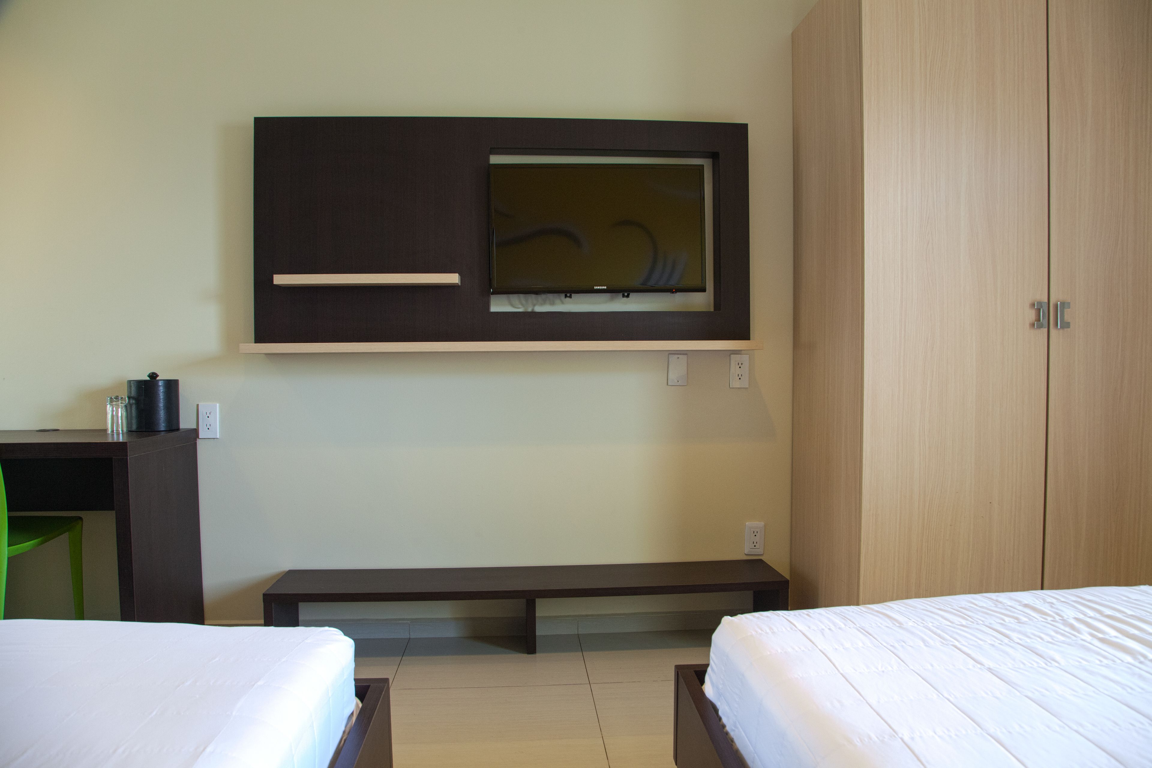 Una habitación de hotel con cama, escritorio, banco y armario.