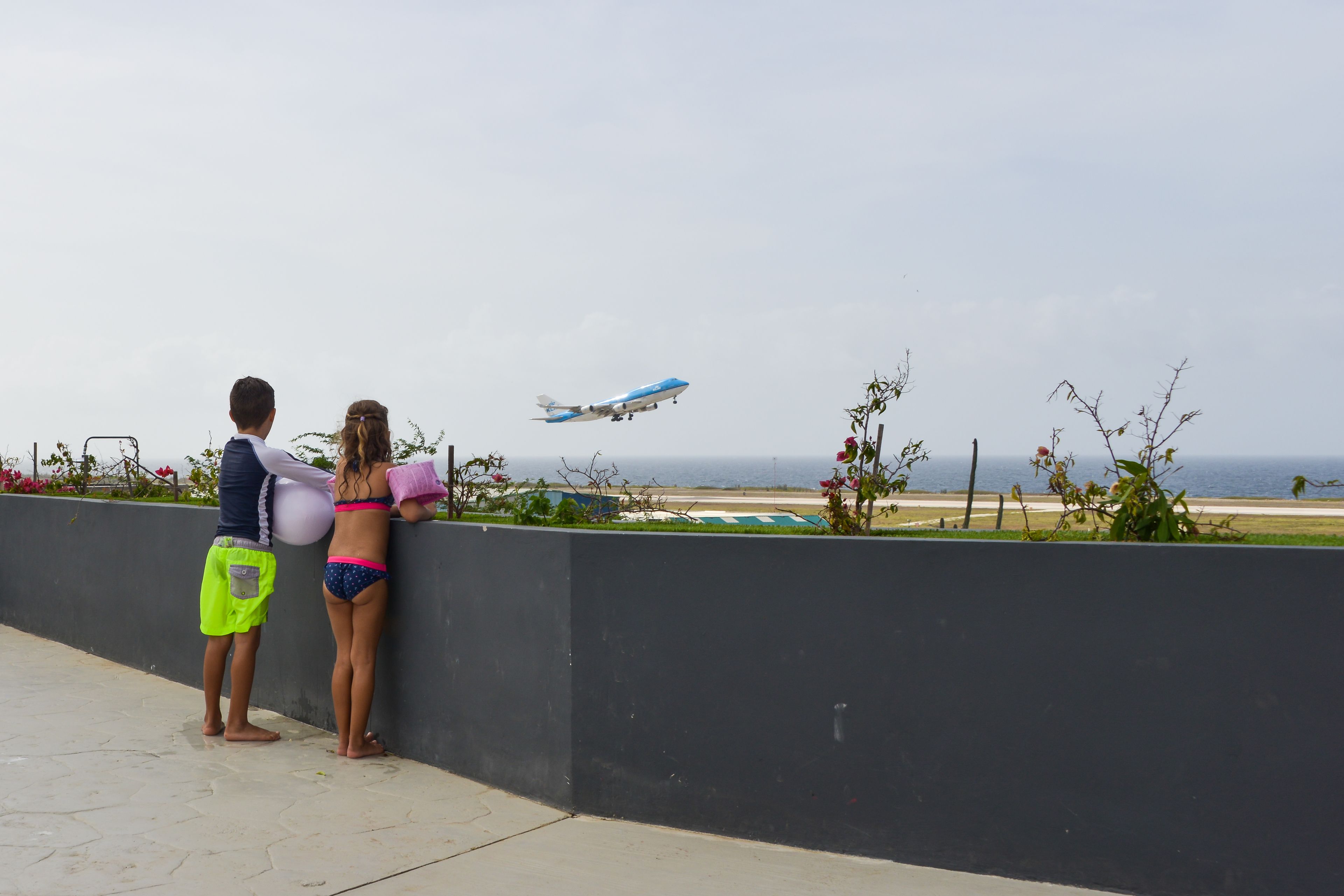 Vista de un avión aterrizando en una pista con un paisaje costero al fondo.