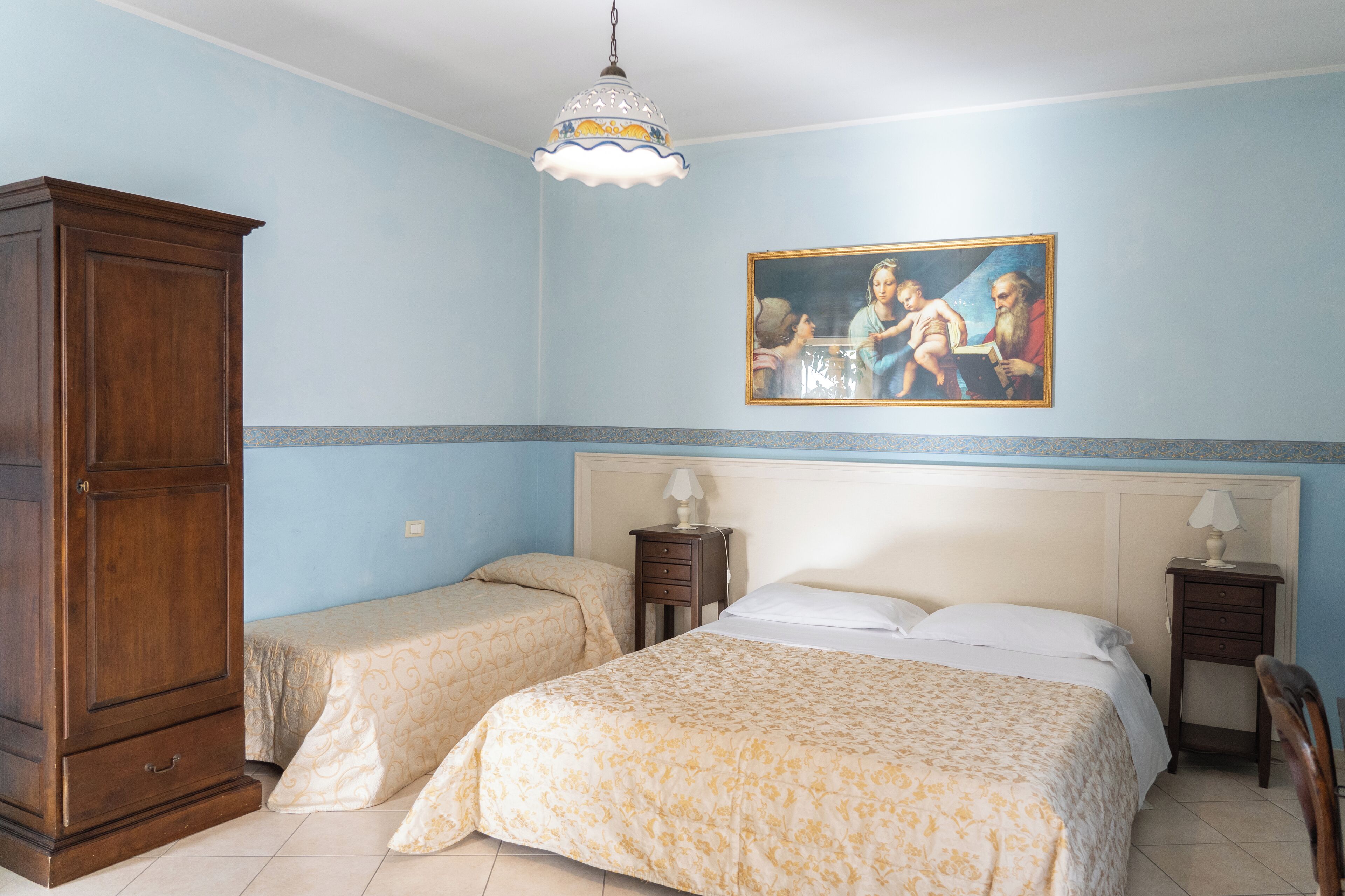 Ein Schlafzimmer mit zwei Betten, einem Holzschrank, einem Bild an der Wand und einem Kronleuchter.