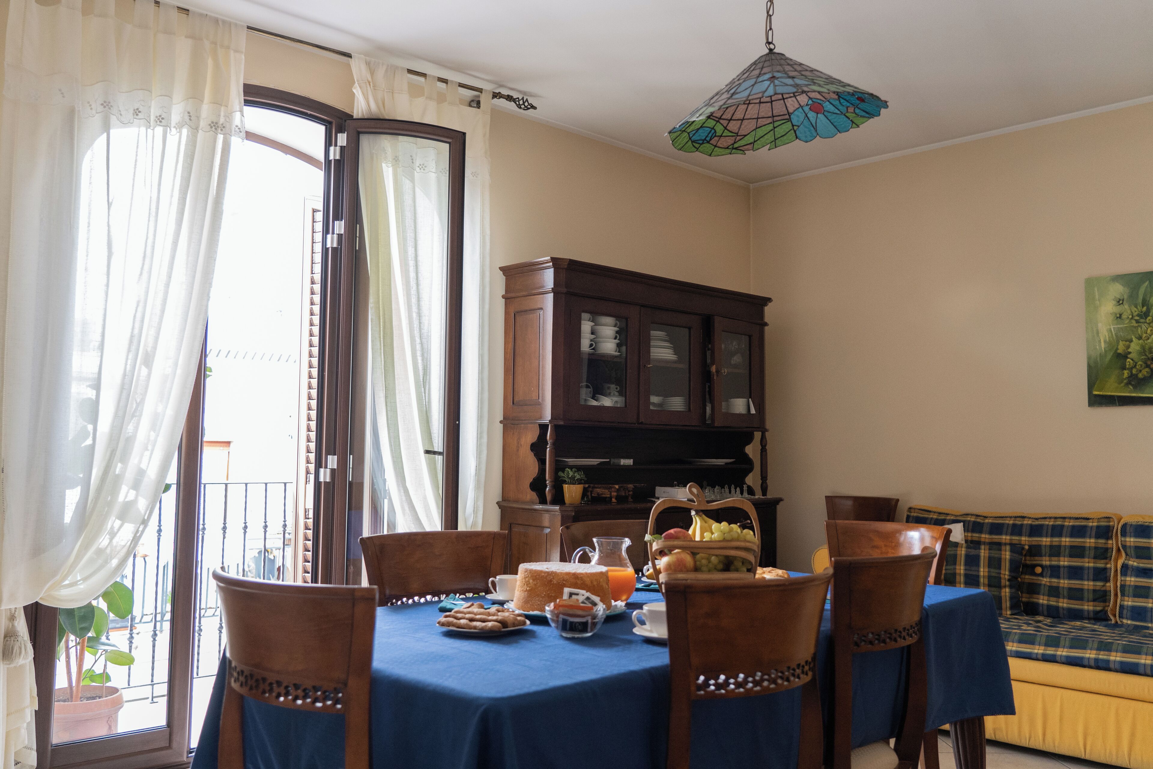 Un coin repas avec une table mise pour le petit-déjeuner, des chaises, un buffet et un canapé.