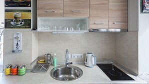 Une cuisine moderne avec des meubles en bois, un évier en acier inoxydable, une bouilloire et une machine à café.