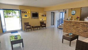 A hotel lobby with a reception desk, seating area, and a staircase leading to other floors. - Akrogiali Hotel (Agistri)