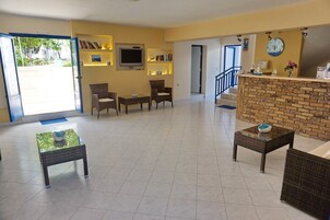 Un hall de hotel con mostrador de recepción, zona de estar y una escalera que sube a otras plantas.