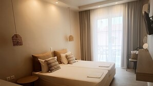 A hotel room with two beds, a small round table, a chair, and a desk with a basket. - Akrogiali Hotel (Agistri)