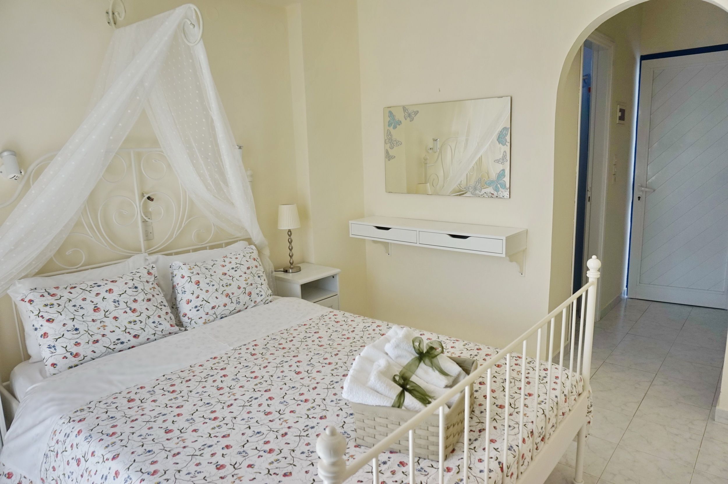 Un dormitorio con cama, mesita de noche y espejo, además de una puerta.