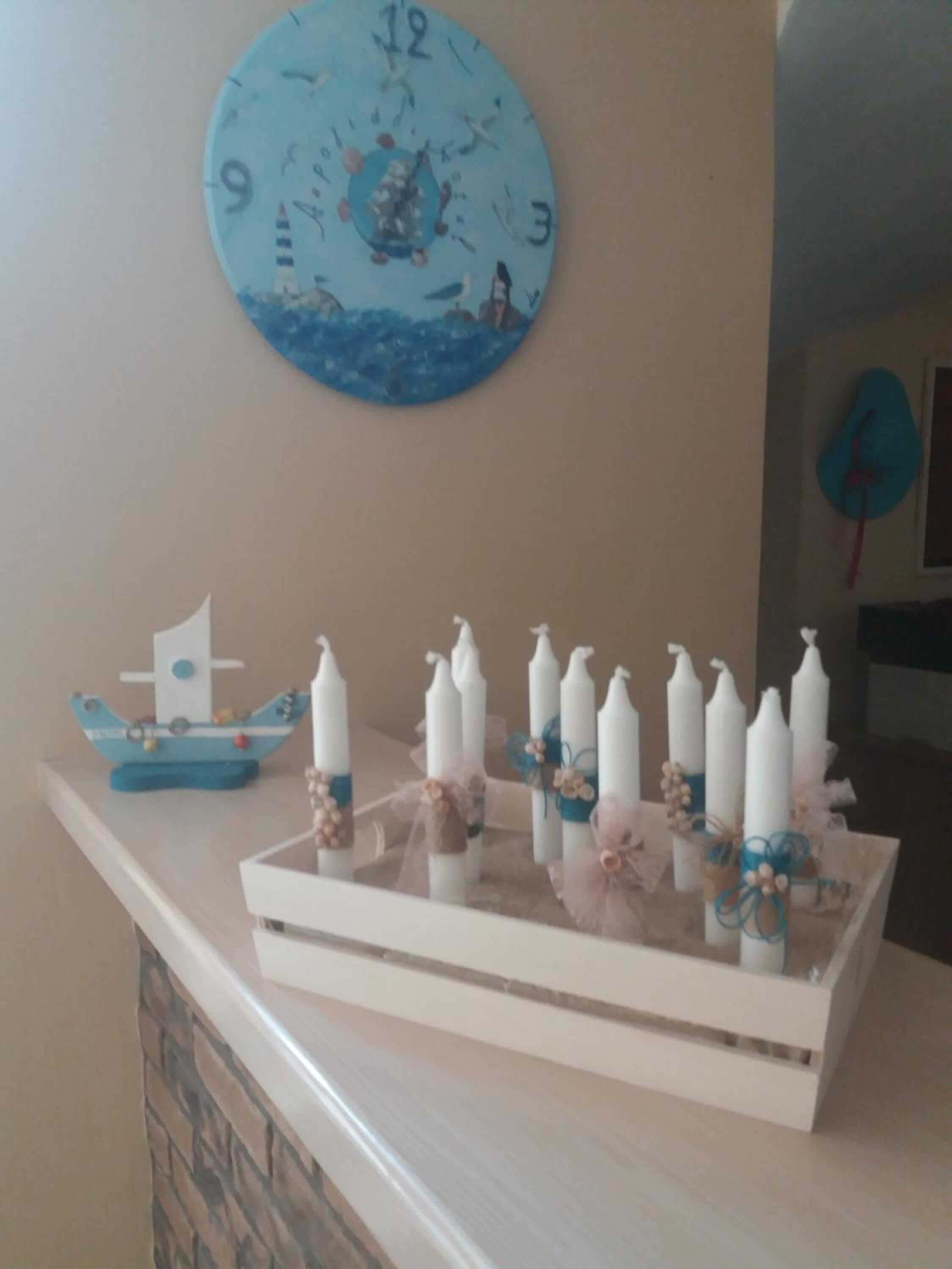 A room with a clock on the wall, a tray with candles, and a small boat decoration.