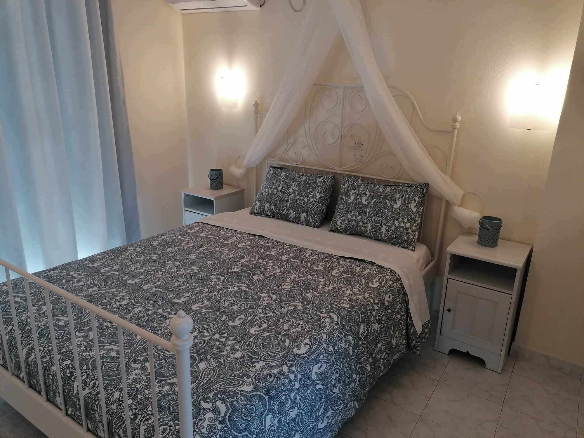 A bedroom with a bed, a nightstand, a bedside table, and a canopy bed.